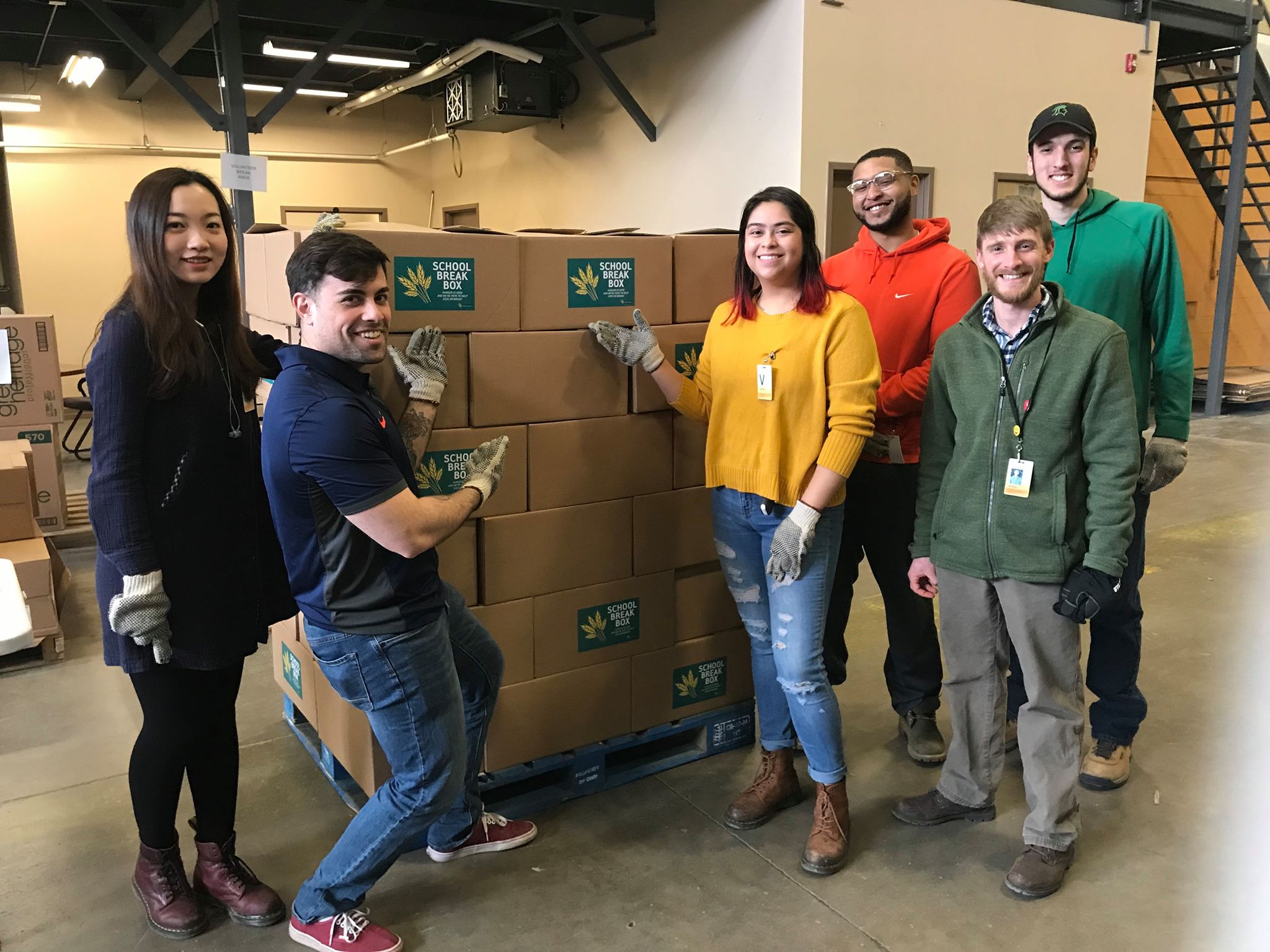 Students stand in front of a large pallet of boxes for donation. Click to learn more about community service.