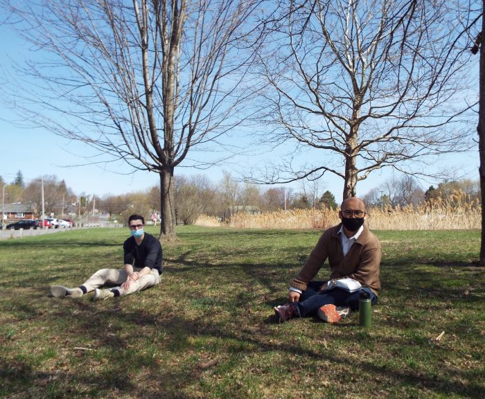 Students sitting in the grass wearing masks